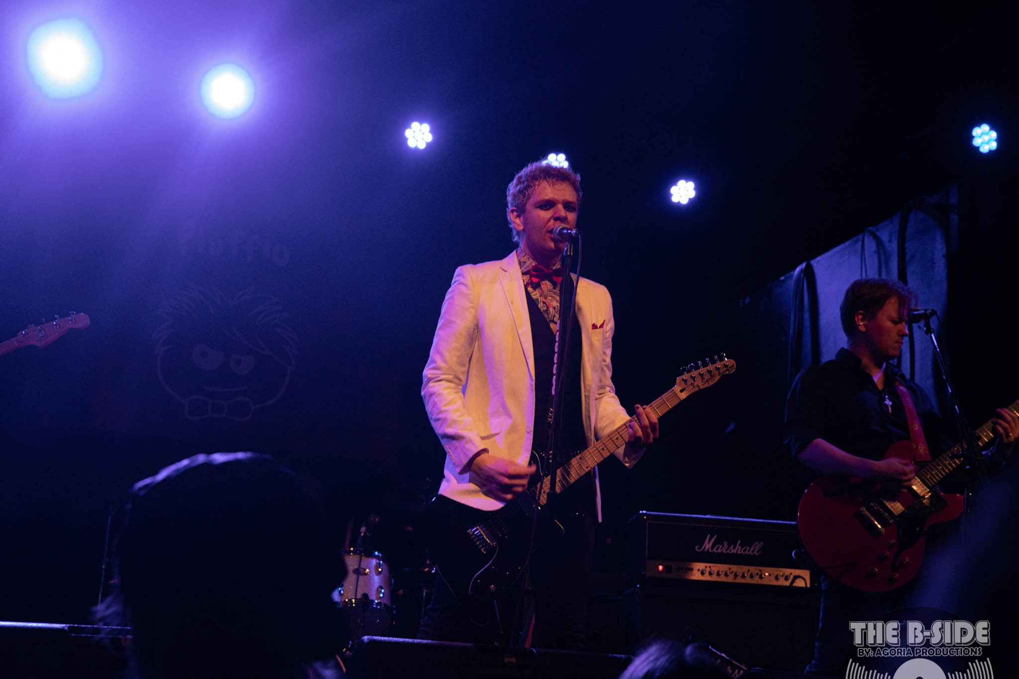 Fluffio singing on stage at Lee's Palace wearing white blazer in Toronto