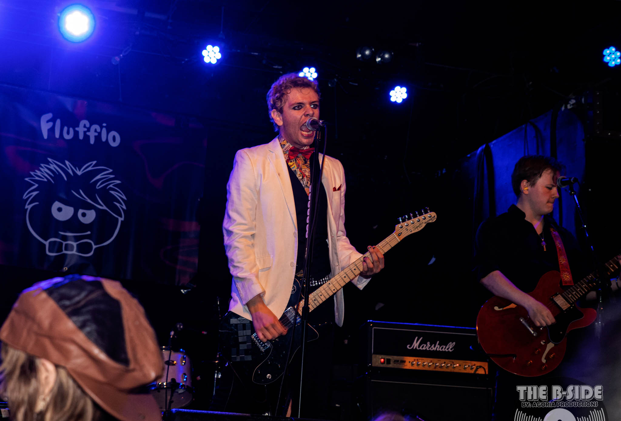 Fluffio singing on stage at Lee's Palace wearing white blazer in Toronto